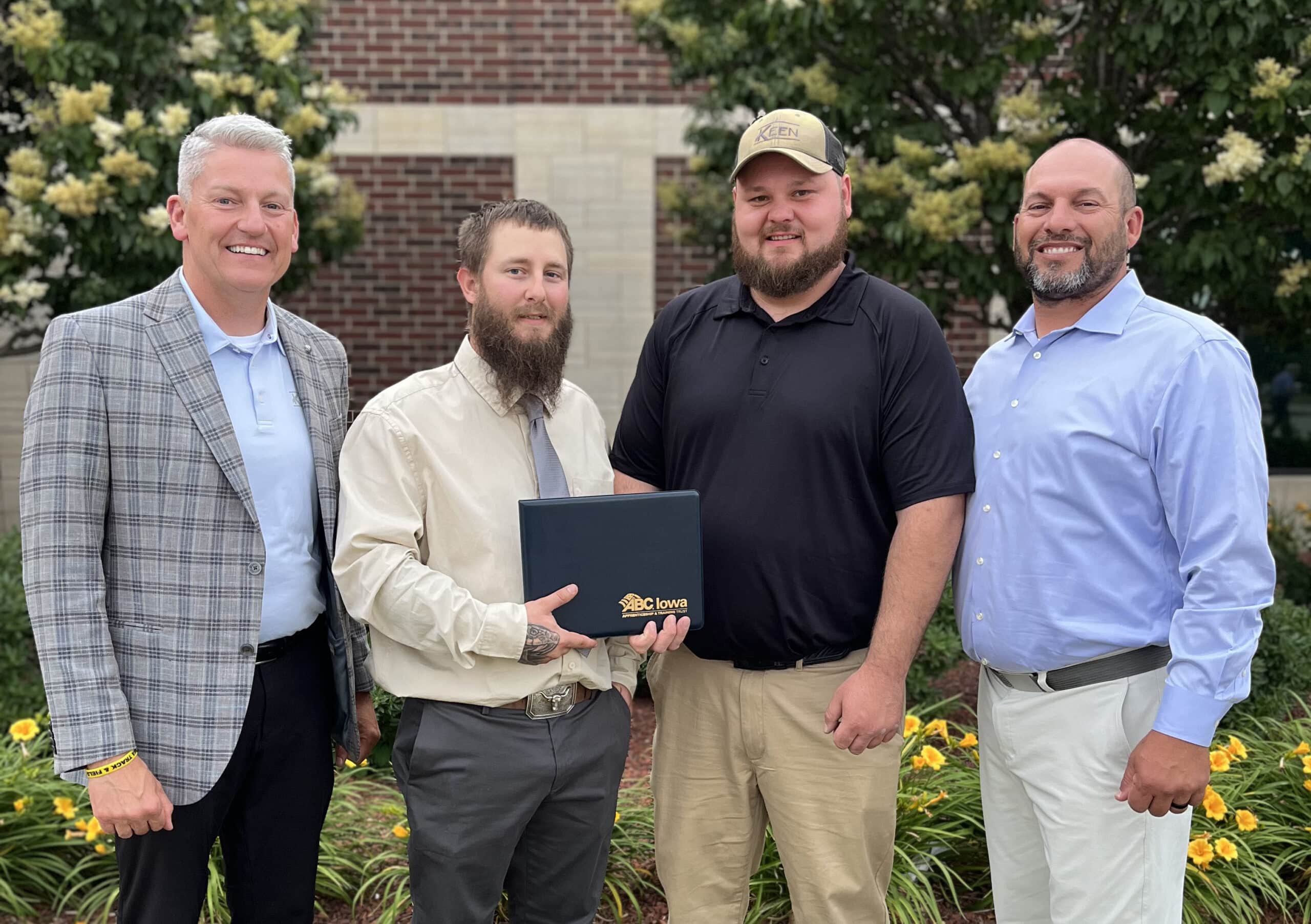 Apprenticeship graduation with four people standing and smiling for the camera