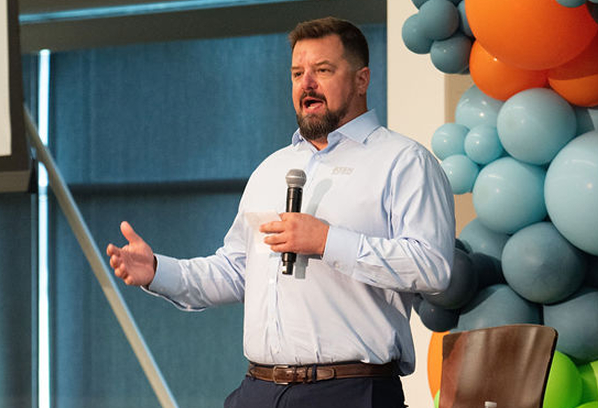 Man standing on a stage, holding a microphone and giving a speech